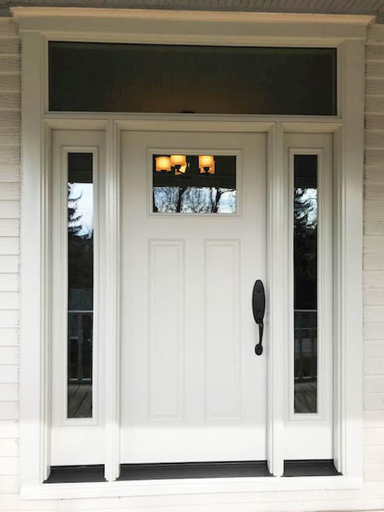 Front entry with white entry door, sidelights, and a transom window.
