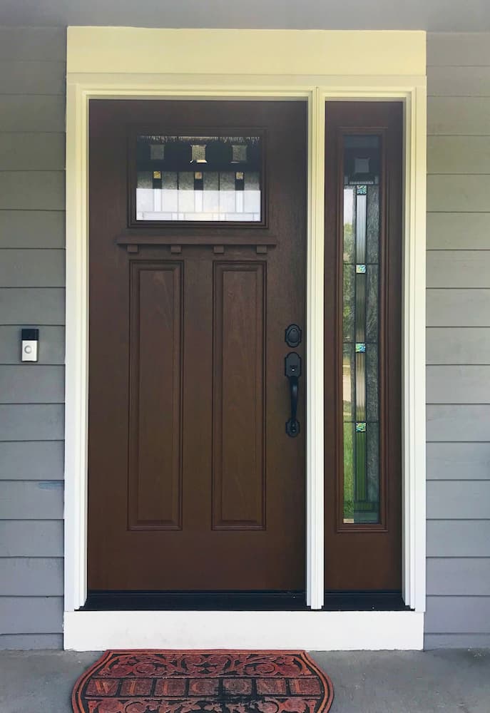New Craftsman-style wood-look fiberglass entry door with decorative glass and sidelight