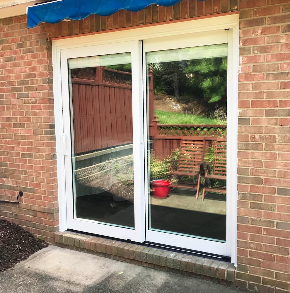 Exterior view of new white clad sliding patio door on red brick home