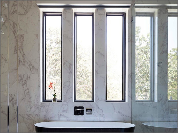 A picture of a bathroom with 3 large windows