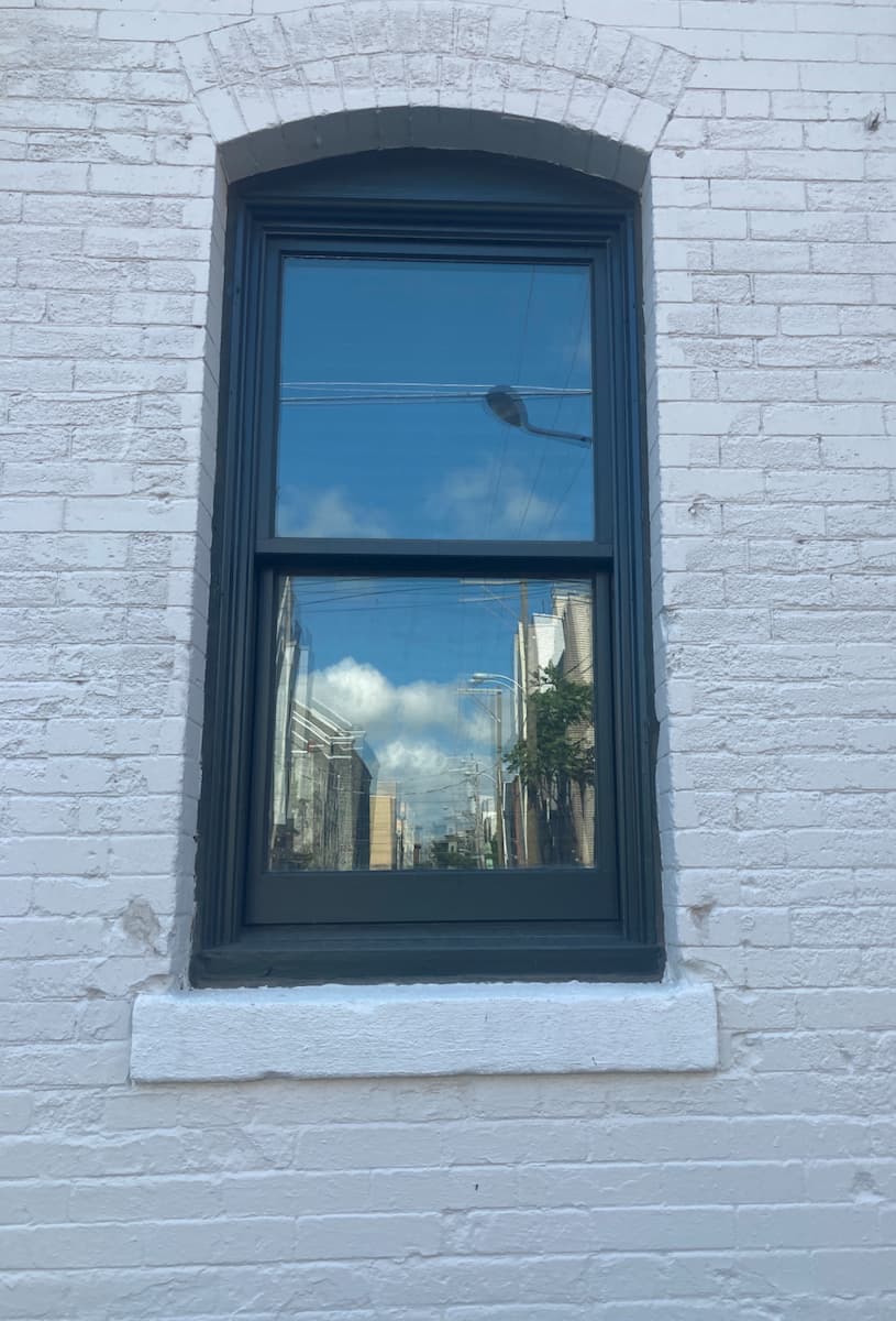 Exterior view of black wood window on white brick building