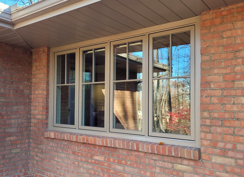 Exterior view of brown replacement casement windows with grilles on red brick home in Dayton