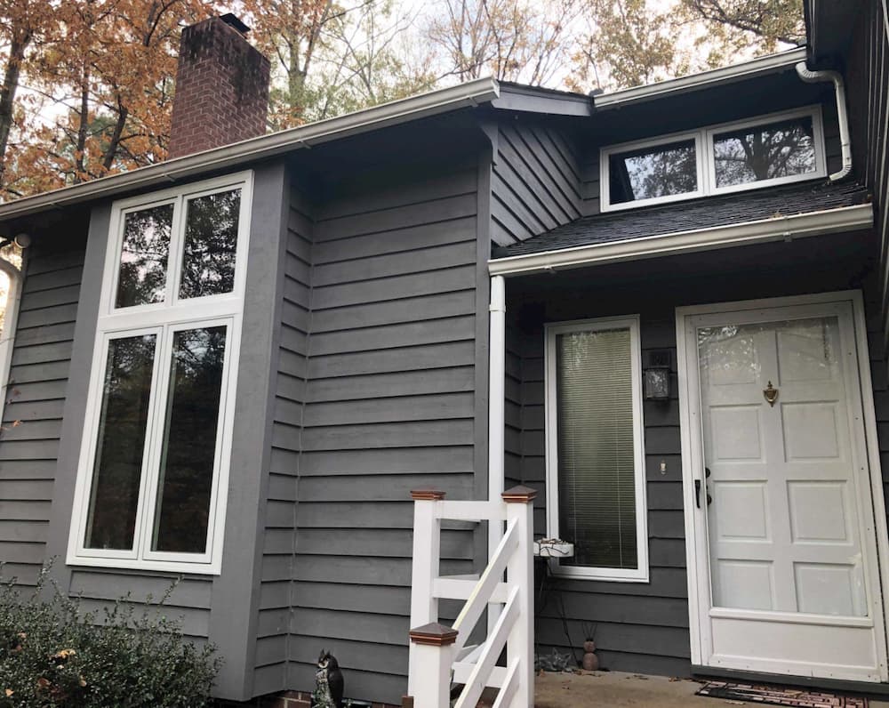 Front exterior view of home with gray siding and new wood casement windows with white trim