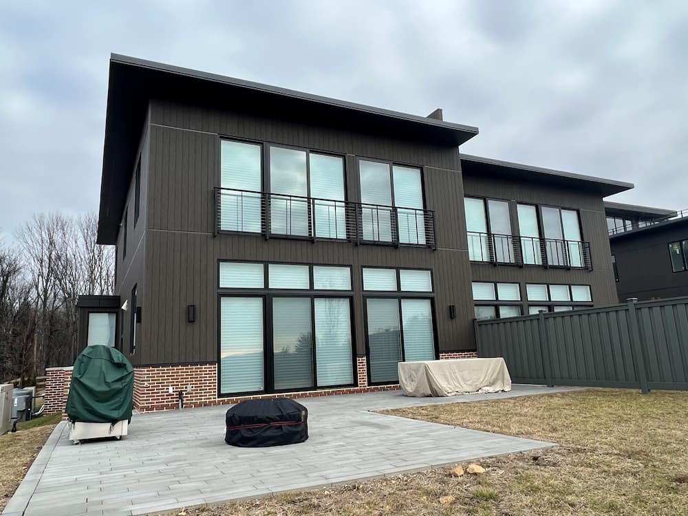 All black, modern townhome building featuring wall of black casement windows and black patio doors