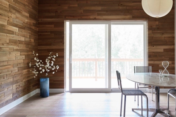White sliding glass doors in dining room with wood-paneled walls