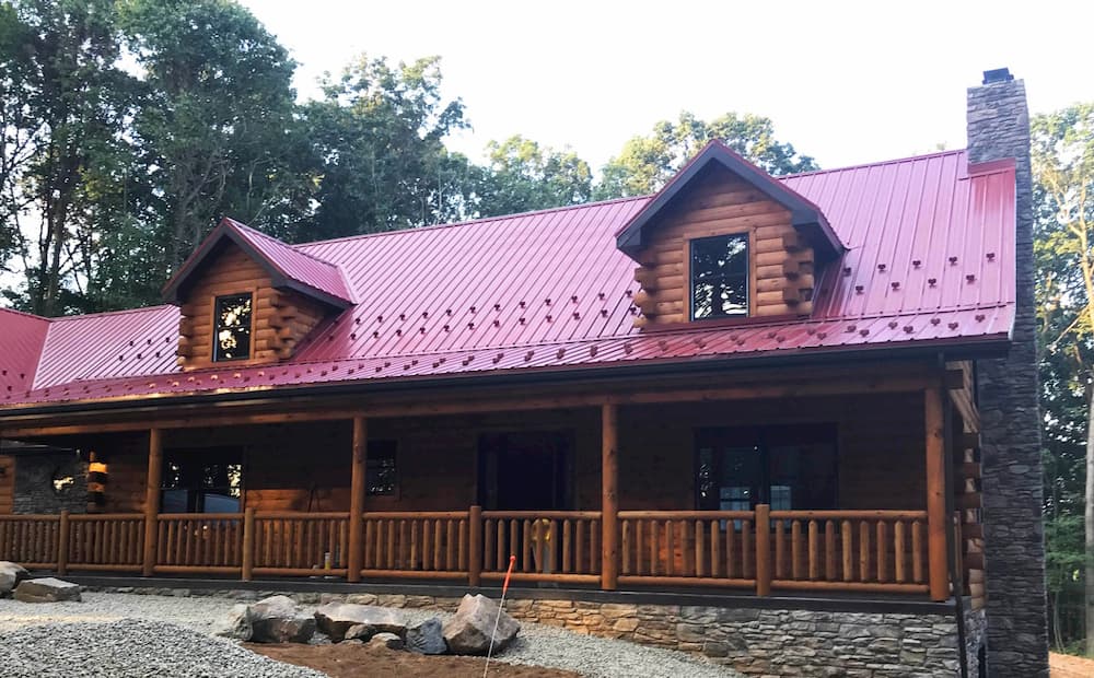 Exterior view of log cabin with red roof and new wood lifestyle series windows