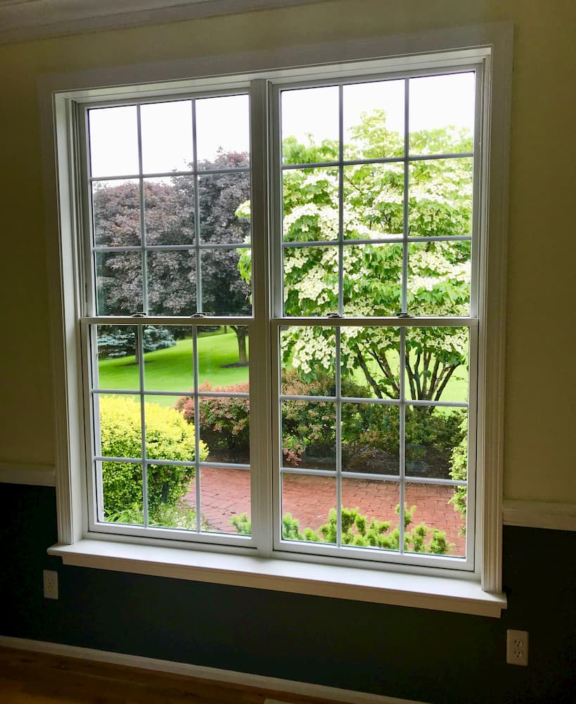 Interior view of two new wood double-hung windows with traditional grille pattern