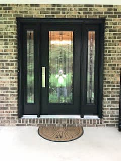 Black full-light wood entry door with full-length sidelights and decorative glass.
