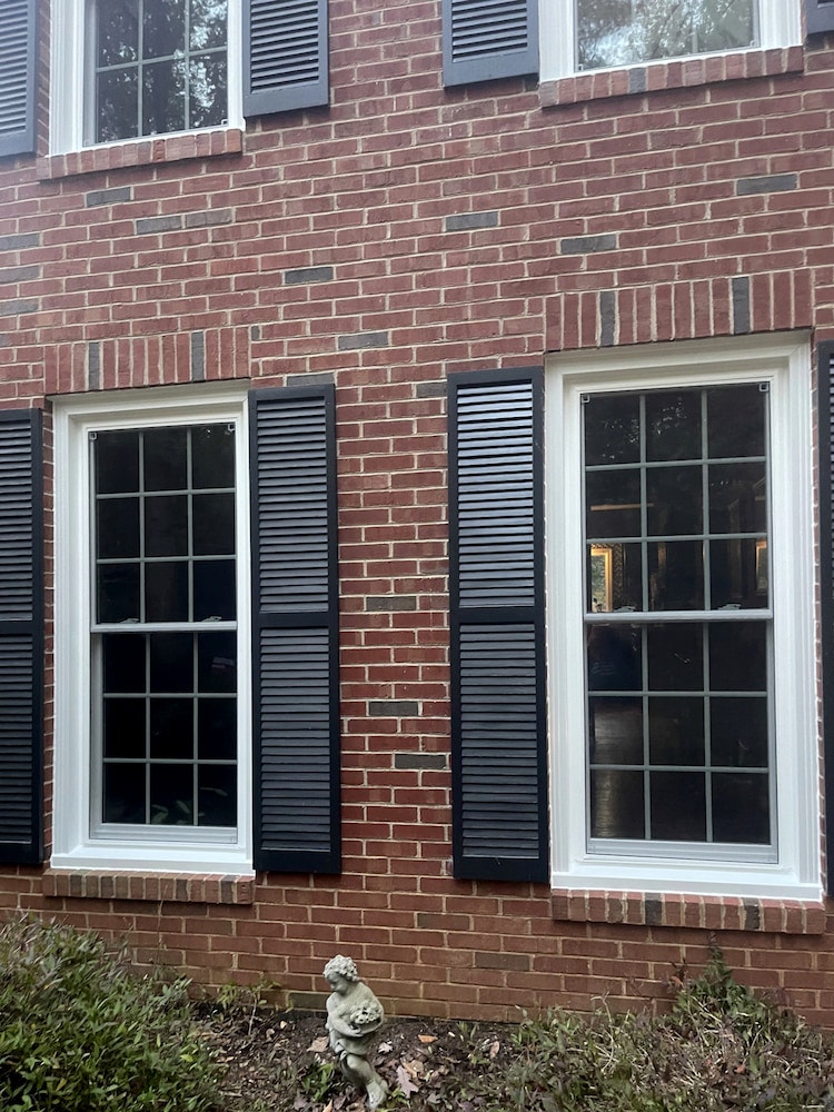 Close-up of Charlottesville home exterior with white double-hung windows and black shutters