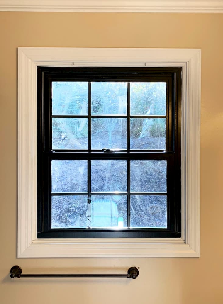 Black double-hung window with traditional grille pattern in a bathroom