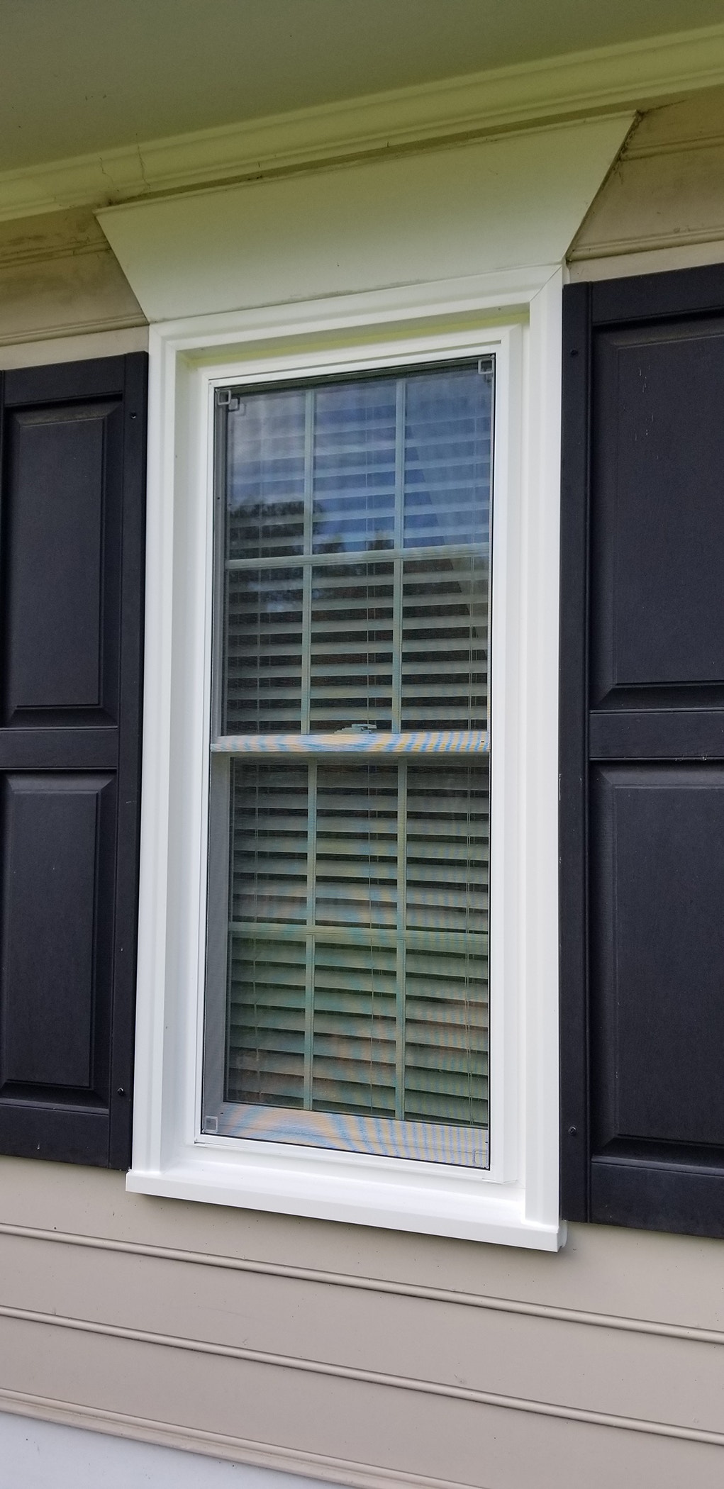 White vinyl double-hung window with black shutters on exterior of Henrico, VA, home
