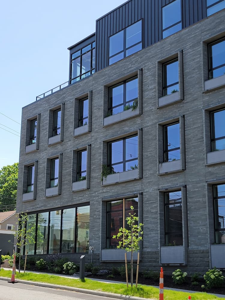 Side view of new gray and black apartment building featuring Pella black fiberglass windows