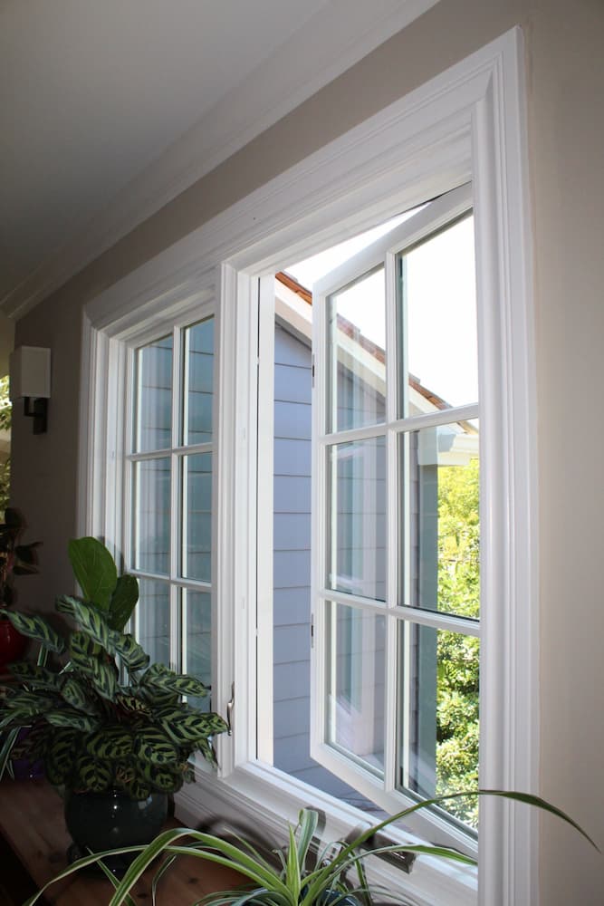 Inside view of upstairs casement window featuring white frames and traditional grilles.