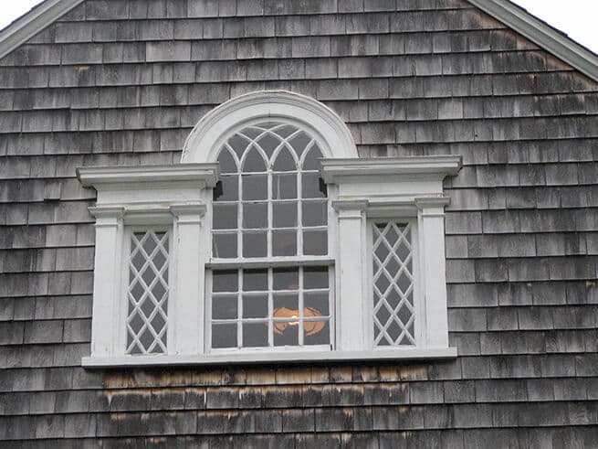 Exterior view of old wood window on shingle-style home