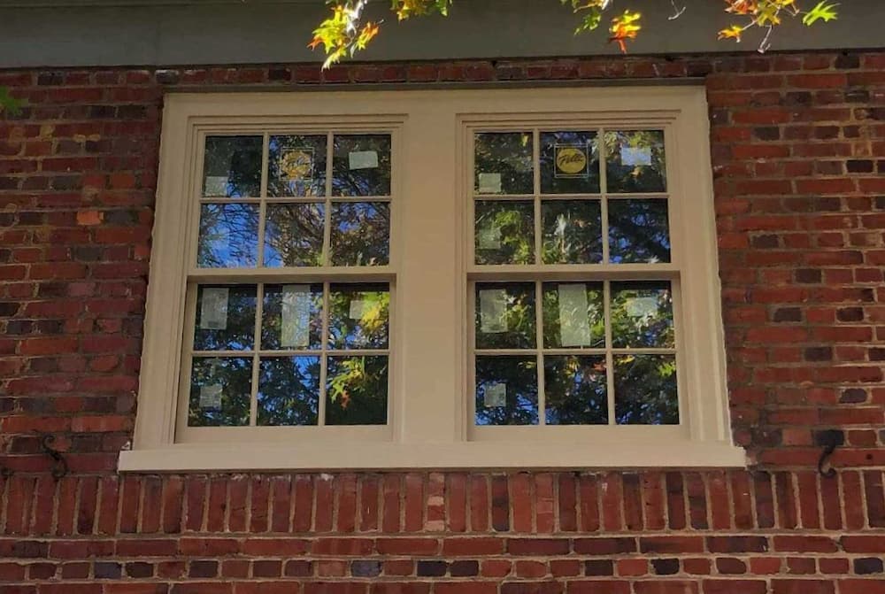 Exterior view of new wood double-hung windows on a red brick home