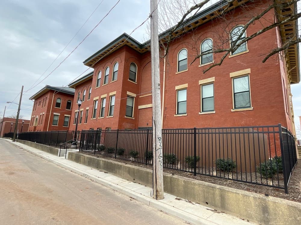 Side of old brick school building turned into apartments with new black Pella windows.