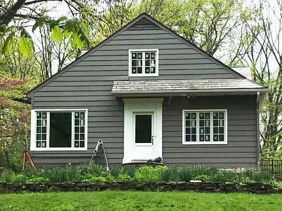 Exterior view of gray Cape Cod-style home with all-new wood casement windows