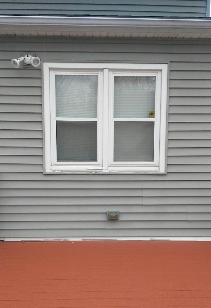 Two double-hung windows on a home with gray siding