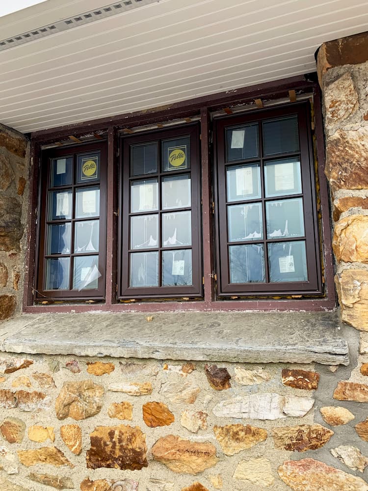 Three brown Pella Architect Series traditional wood windows with grilles in a row