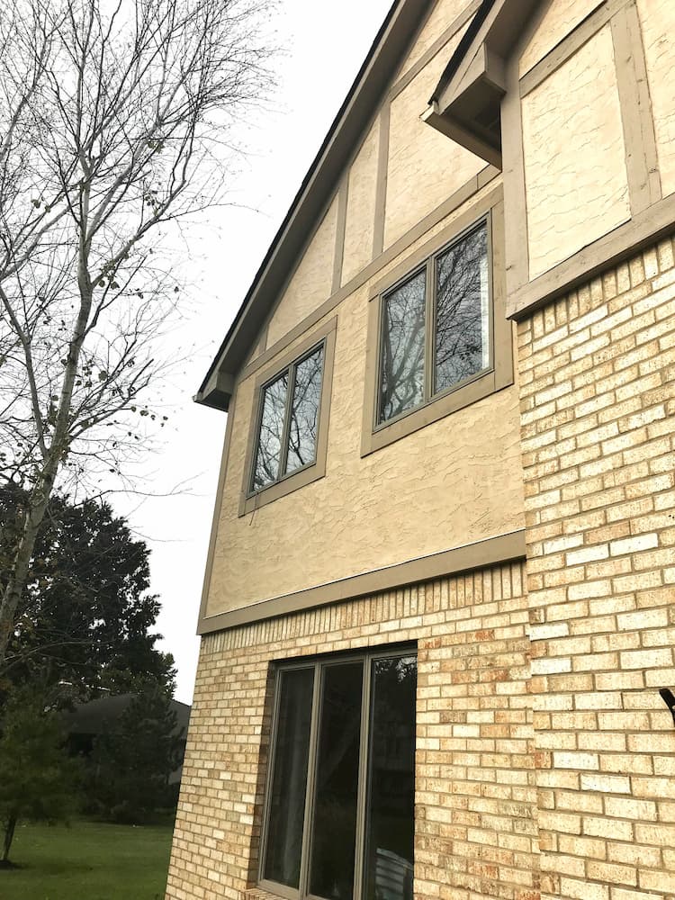 Old brown casement windows on the side of a Tudor-style home