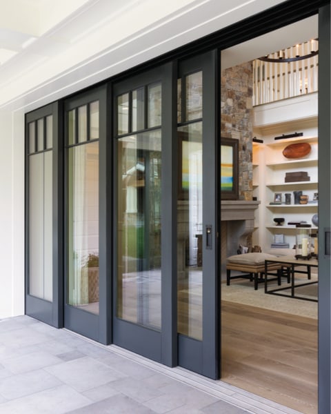 A black-framed, multi-panel sliding glass door brings the outdoors in