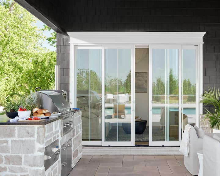 White sliding patio door from the exterior with outdoor kitchen and table