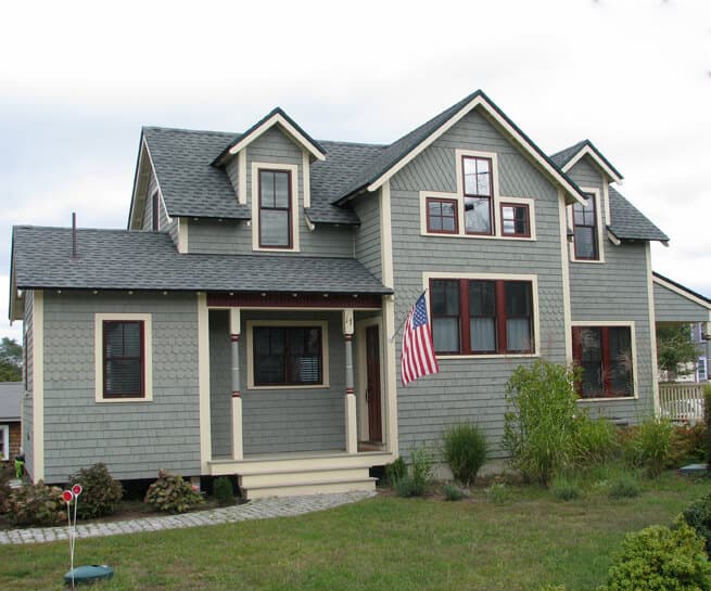 Front exterior view of shingle-style home with brick-red exterior clad wood windows