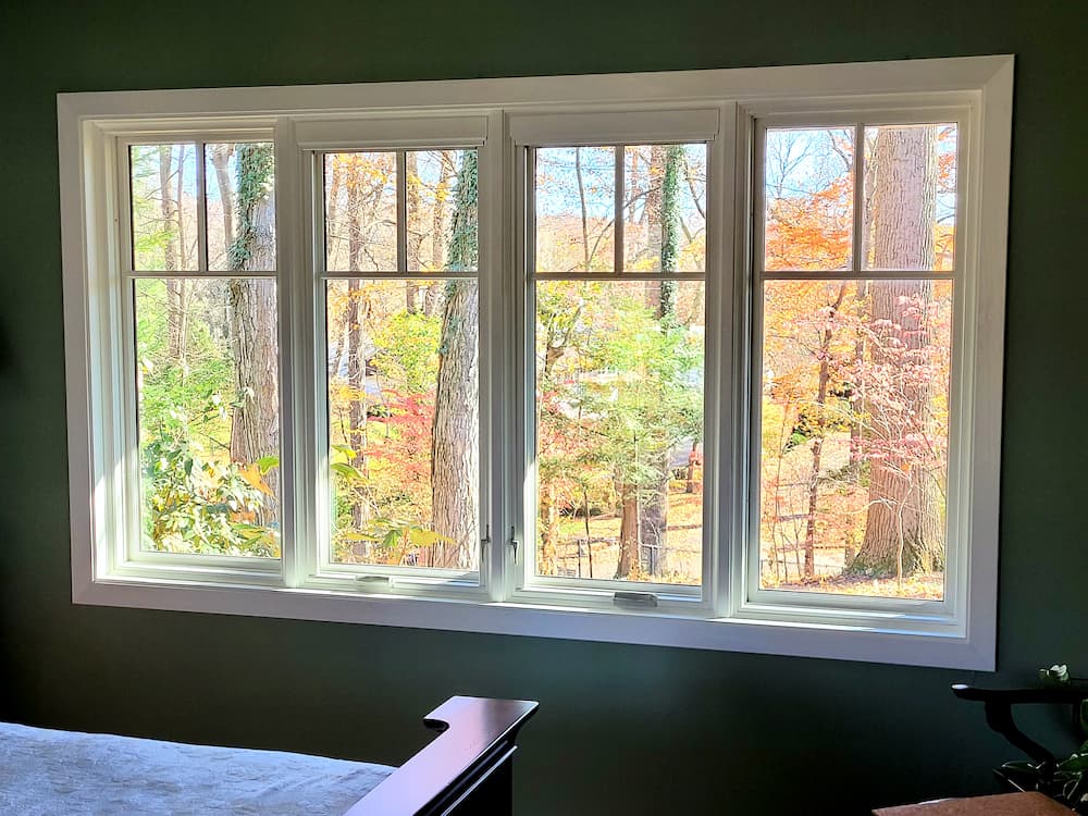 Interior view of four side-by-side white replacement casement windows with fall foliage backgorund