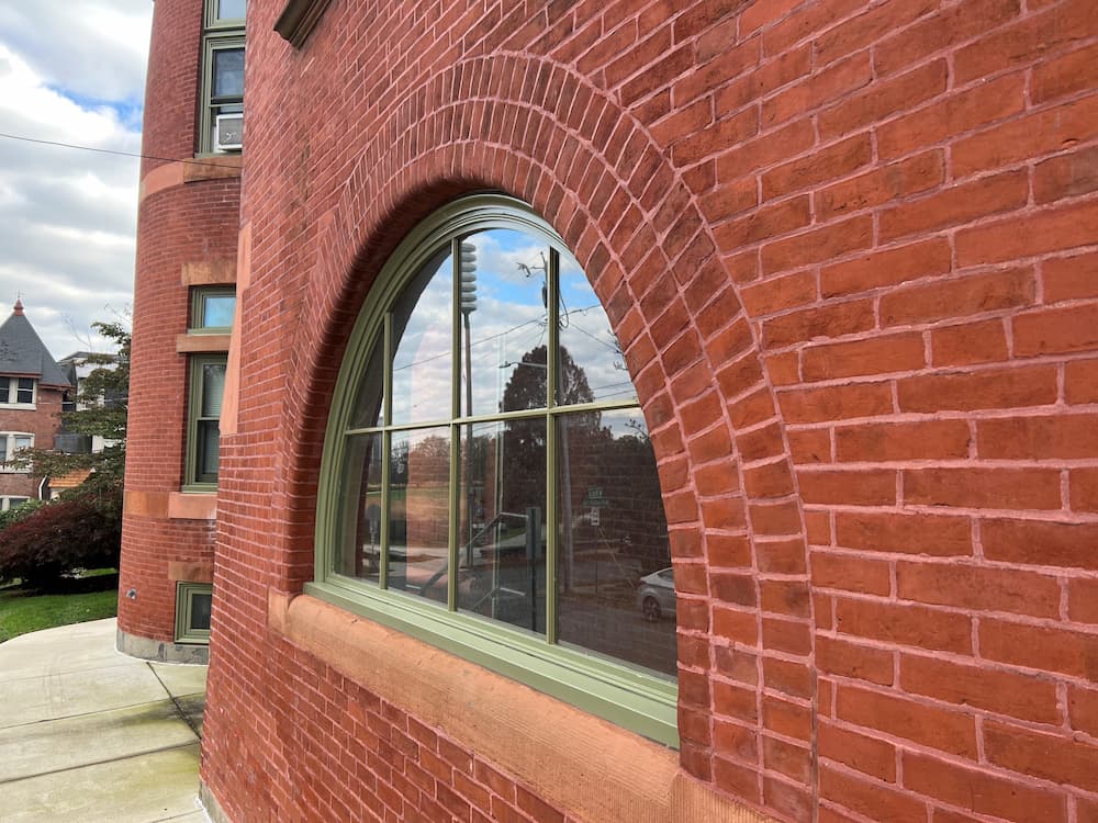 Close up of new Pella arched picture window with grilles in Architect Reserve wood