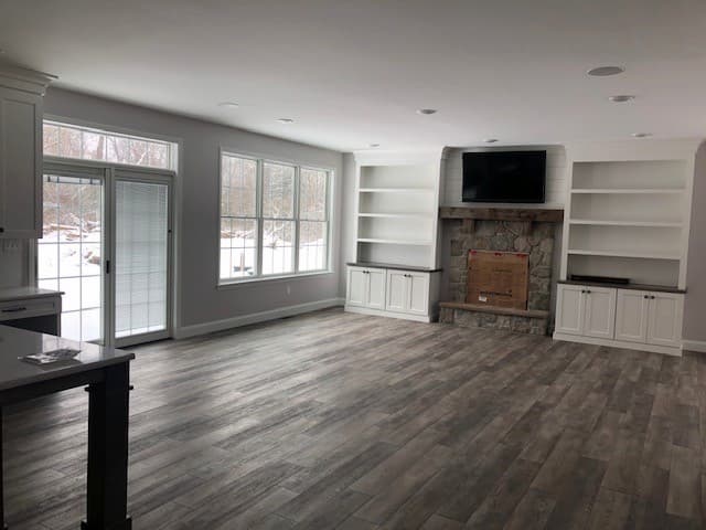 View of an empty living room with a sliding patio door and three double-hung windows
