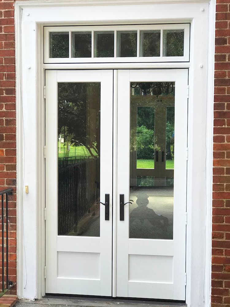 Exterior view of new wood French patio doors and transom window on historic red brick home