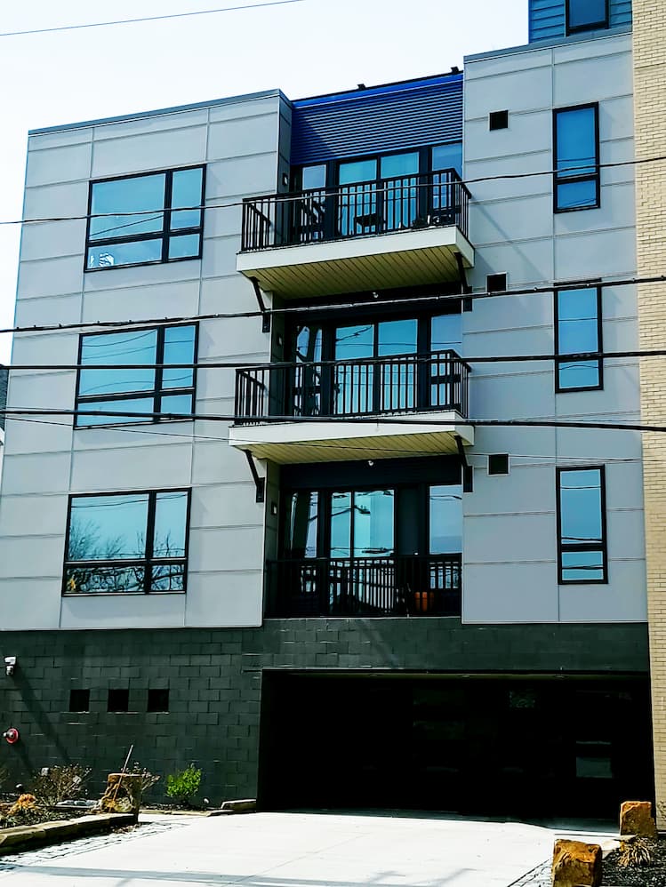 Side view of modern apartment building featuring black casement and awning windows