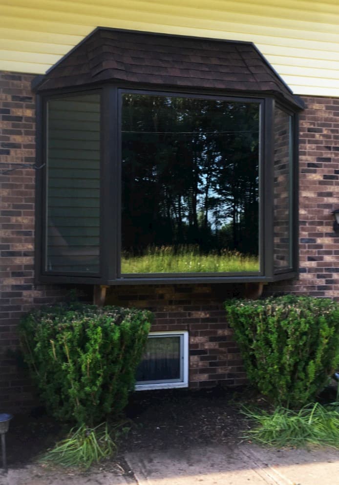 Exterior view of new wood bay window with black finish on a brick home