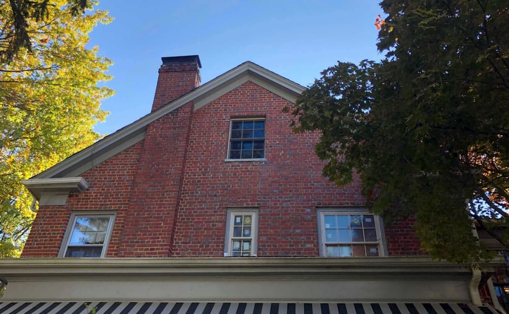 Exterior view of new wood double-hung windows on the second story of a red brick home
