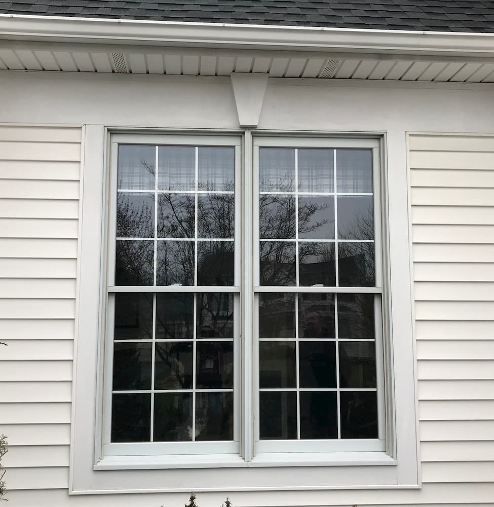 Exterior view of old double-hung windows on house with white siding