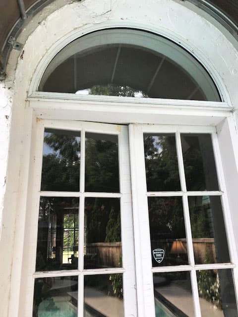 Exterior view of old white French door and arch transom window