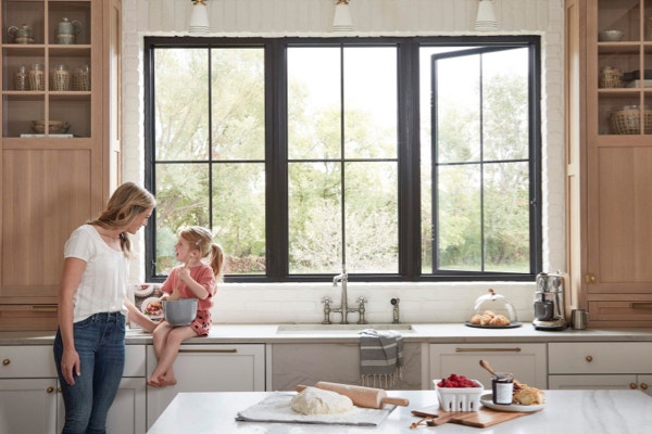 Mother and daughter bake together in kitchen with open grid windows