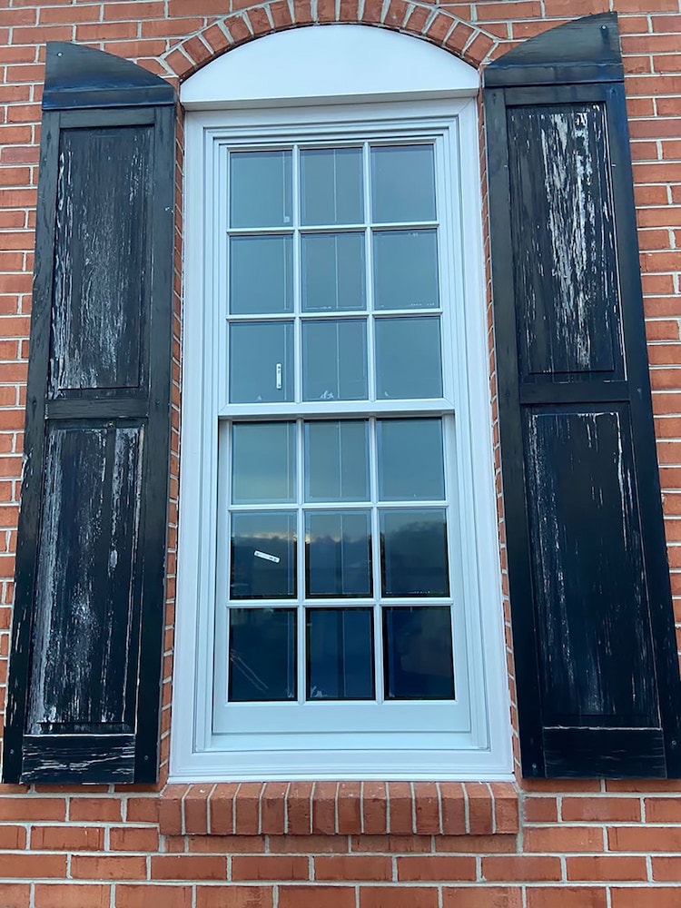 Close-up of double-hung window with black shutters
