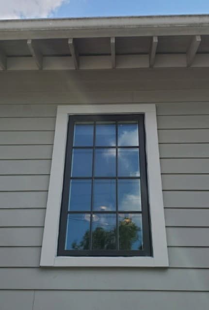 Exterior view of black wood double-hung window on home with gray siding