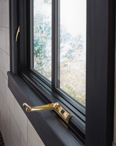 Brass window crank on black casement window