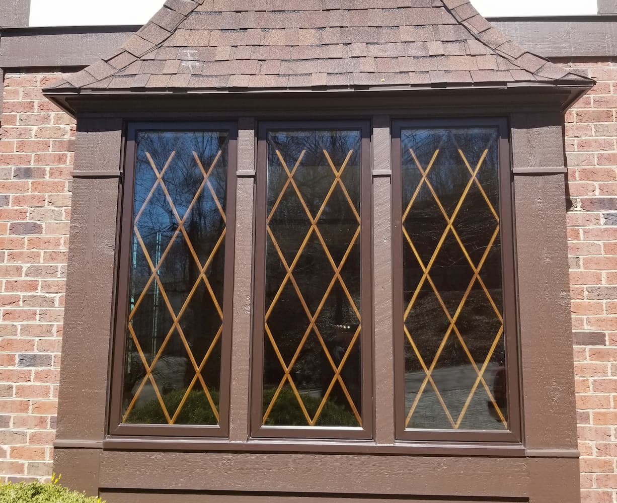 Exterior view of three new wood windows with diamond grille pattern