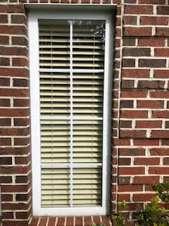 Old white casement window on red brick home