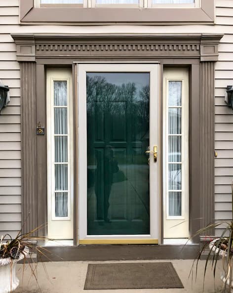 Old entry door with storm door and two full-light sidelights with grilles