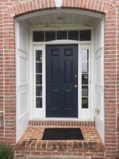 Old entry door with traditional sidelights and transom on a red brick home