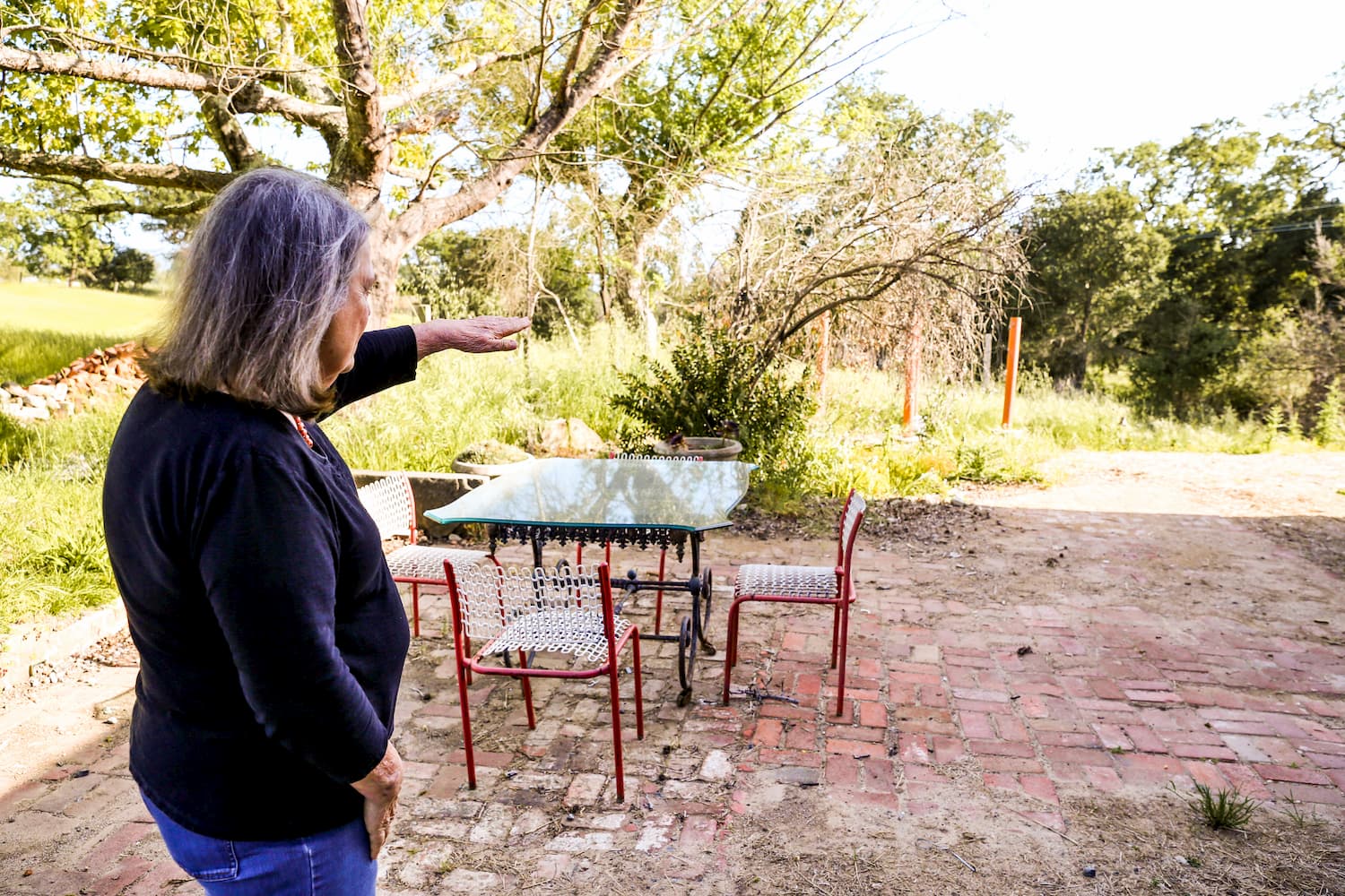 Older woman standing on brick patio surveying backyard