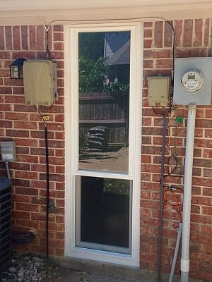 tall narrow window on a brick home with an electric meter to the right