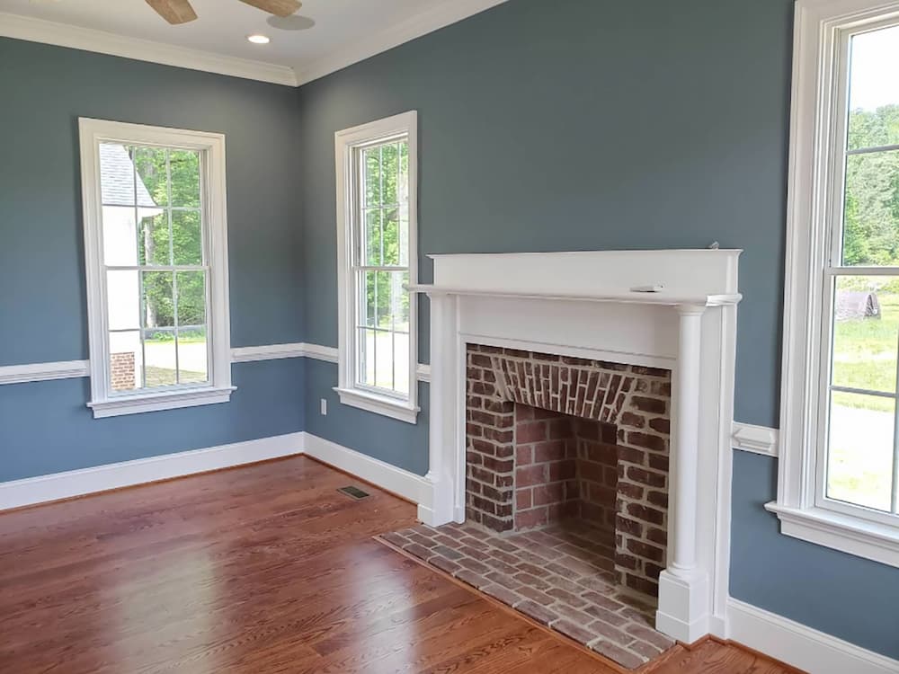 Fireplace in New Kent new build surrounded by white wood double-hung windows 