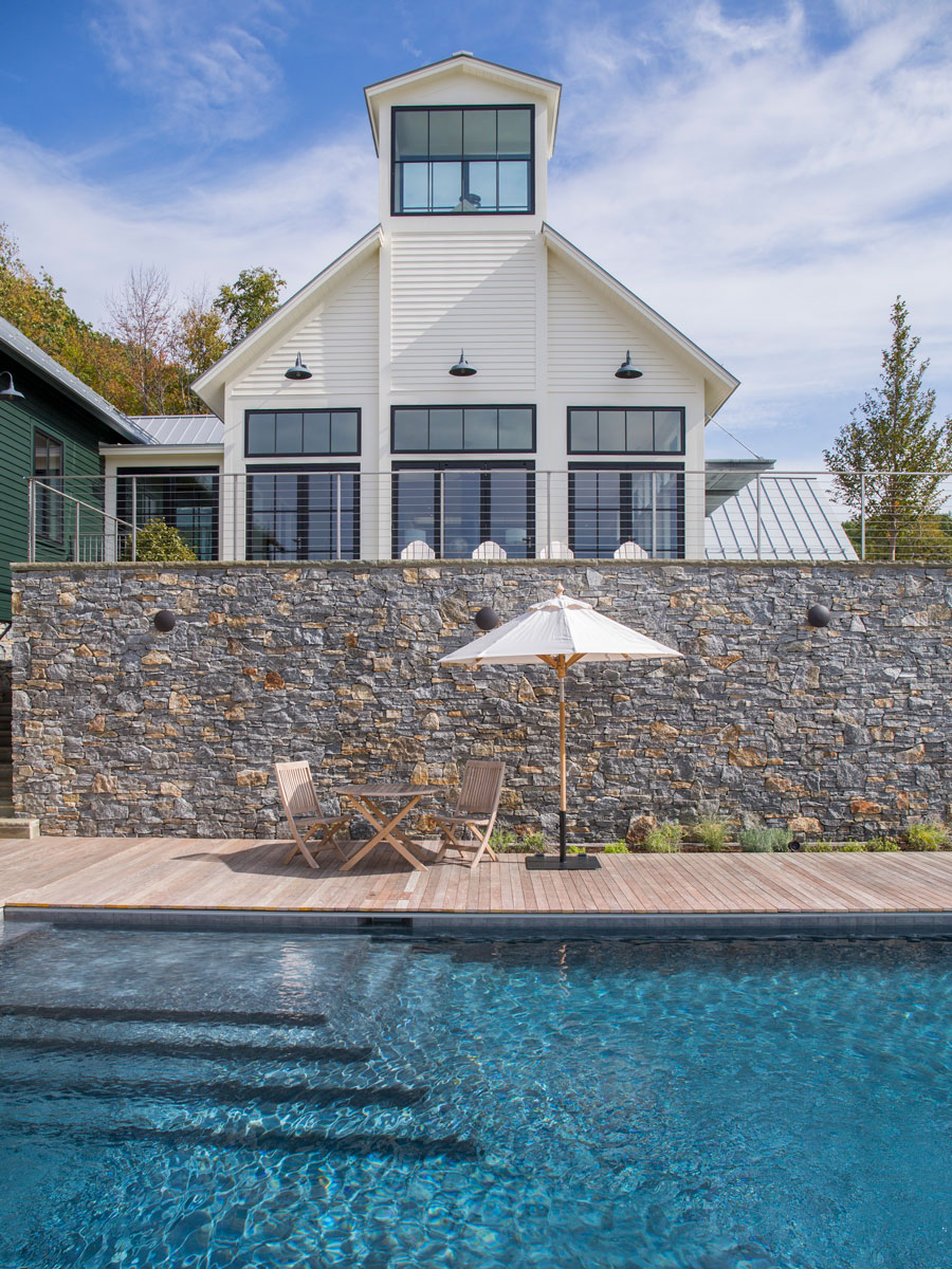 Poolside patio of home with black wood windows and patio doors in Williamstown, MA