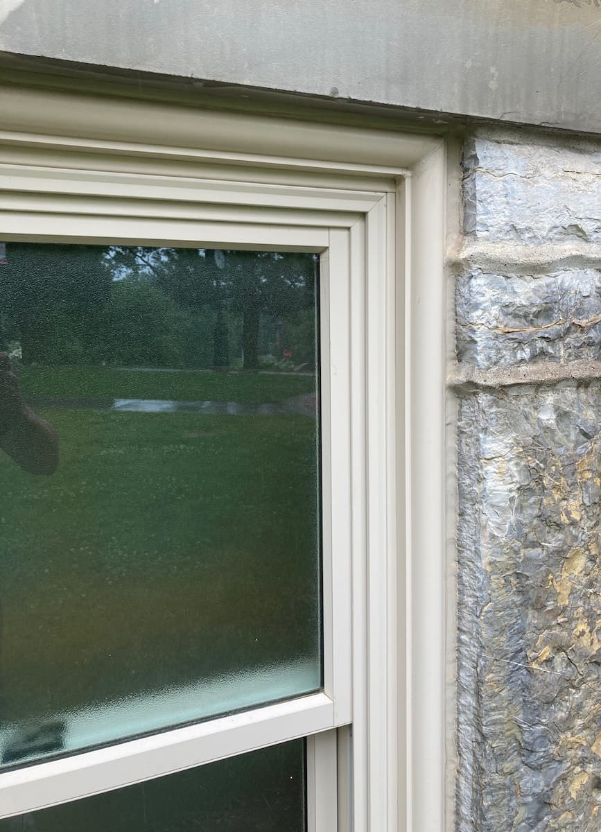 Close-up of exterior trim work of new aluminum-clad wood windows against stone facade