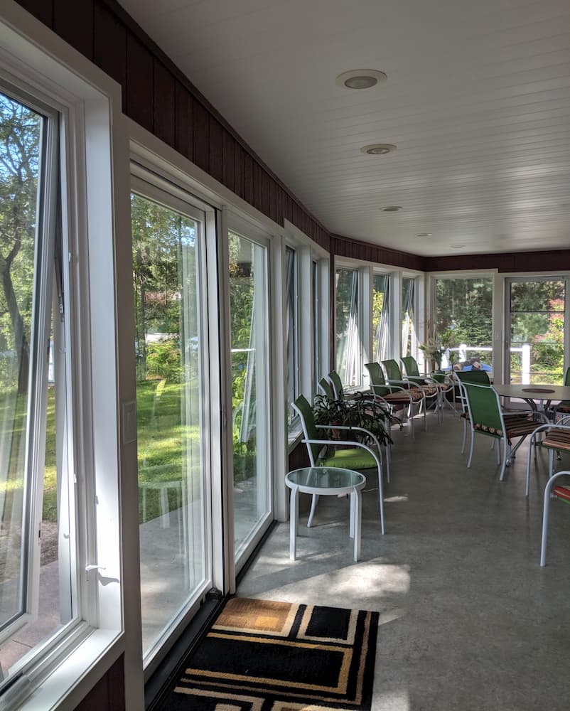 Interior view of porch with a wall of white wood awning windows